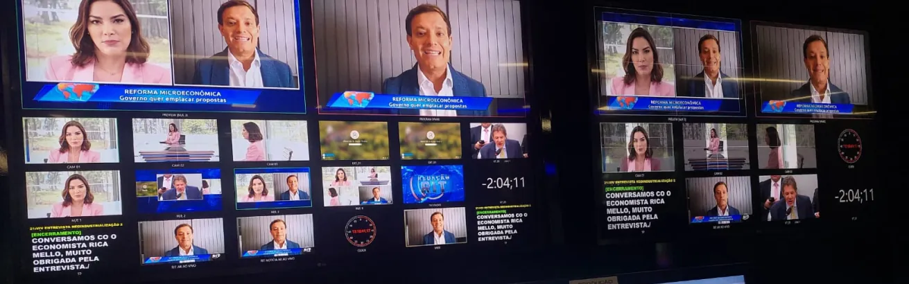 Monitores de um estúdio de TV durante entrevista ao vivo com Rica Mello sobre reforma microeconômica